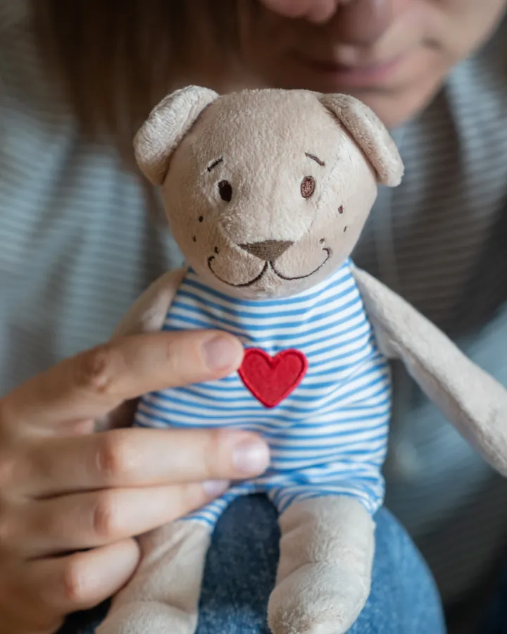 Donna che stringe un orsetto di peluche con un cuore